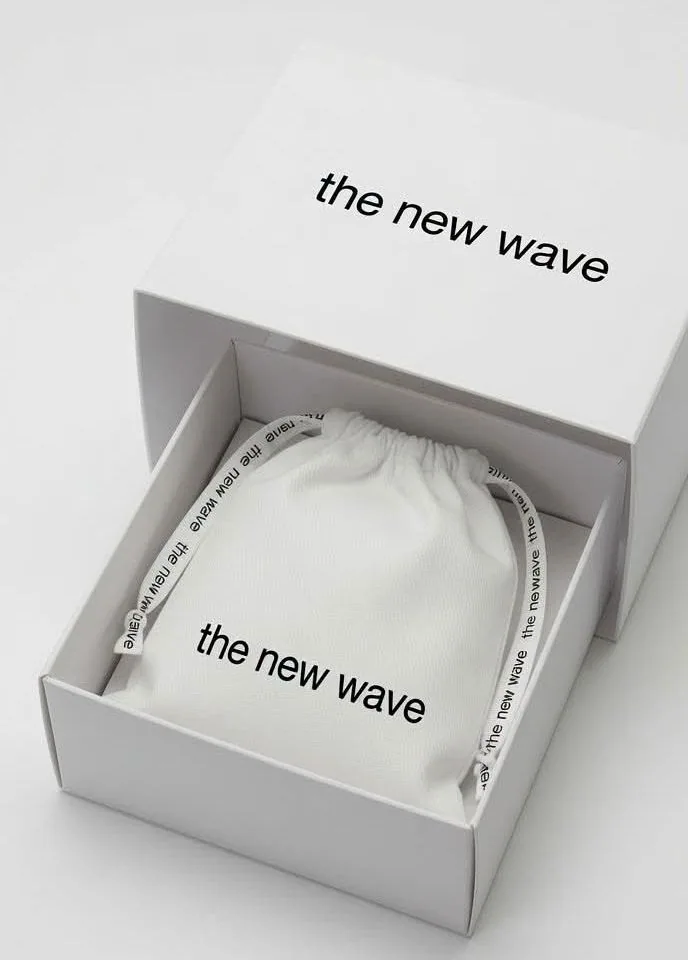 The new wave presentation box with its drawer open, holding a white drawstring pouch printed with the new wave