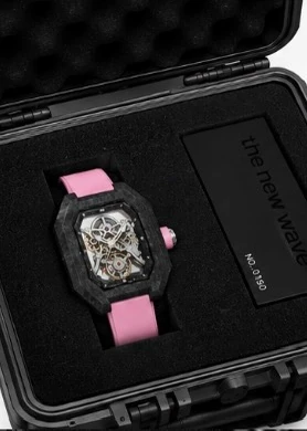 Project 2 with the pink strap in its black presentation case, beside the numbered the new wave plate
